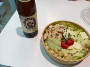 A Caesar salad and a bottle of German wheat beer on a table in the Dürer Lounge at Nuremberg Airport]